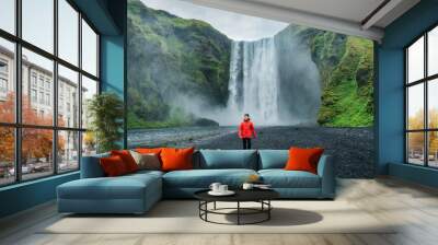 Powerful Skogafoss waterfall and male tourist walking in summer at Iceland Wall mural