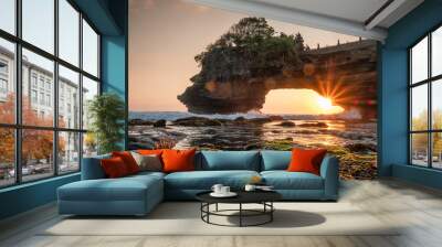 Sunshine through of rocky cliff on seashore at sunset Wall mural