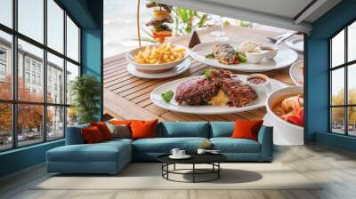 Variety of food, roasted pork ribs, beef steak, seafood and spicy soup on dining table Wall mural