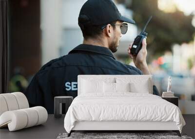 Radio, man and a security guard or safety officer outdoor on a city road for communication. Back of a person with a walkie talkie on urban street to report crime for investigation and surveillance Wall mural