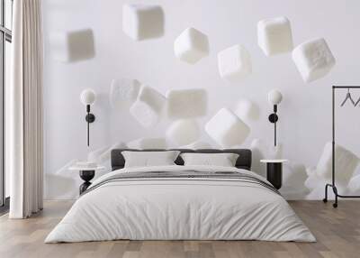 A close-up of falling sugar cubes against a light background. Wall mural