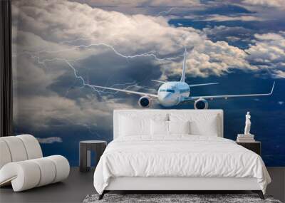 An airplane is flying over low clouds with blue sky - Airplane taking off from the airport - Travel by air transport Wall mural