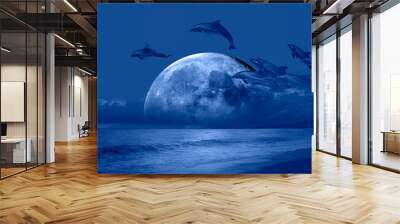 Silhoutte of dolphins jumping up from the sea with blue full moon 