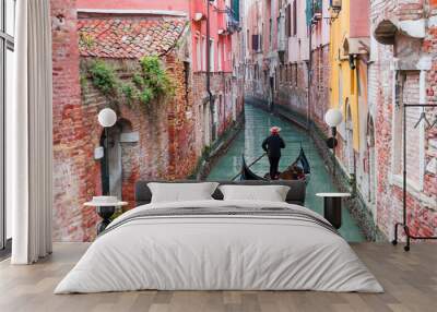 Venetian gondolier punting gondola through green canal waters of Venice Italy Wall mural