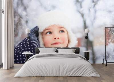 Portrait of a cute little girl in the snowy park. Wall mural