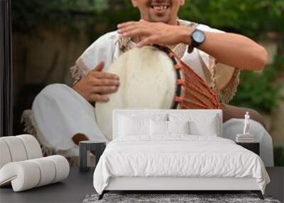 Portrait of young latino percusionist playing african drums Wall mural