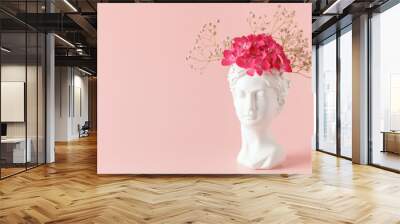 Creative art concept plaster head ancient sculpture with hair fresh flowers gypsophila and hydrangea on pink background. Copy space Wall mural