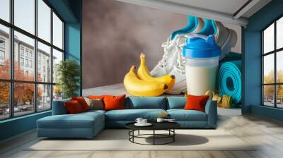 Sport equipment and food -  mat, gym shoes, block,  belt,  protein, banana, apple. Fitness concept. Copy space Wall mural