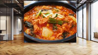 A bowl of Kimchi jjigae, a traditional Korean stew, with vegetables and tofu, served in a black bowl. Wall mural