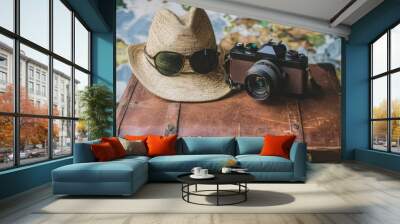 Vintage suitcase, camera, sunglasses, and hat against a world map background. Wall mural