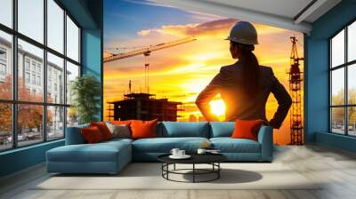 Silhouette of a female engineer in a hard hat at sunset, with a construction site in the background, symbolizing progress. Wall mural