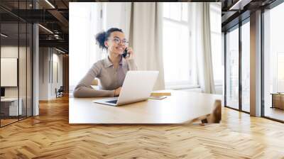 A female freelance designer startup working in an office laptop communicating with a colleague online Wall mural