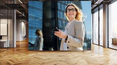 A woman entrepreneur answers a client's email using a phone. Glasses on his face, goes to work in a new office. Wall mural