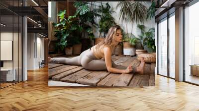 Balance stretching exercises for body flexibility. A coach of European appearance trains in the asana pose. A young woman is doing yoga in the studio. A healthy lifestyle. Wall mural