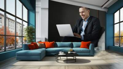 the manager prints a text message on the laptop computer. social network chat with partners. The economist is a man in a business suit sitting in a stylish modern office. Wall mural