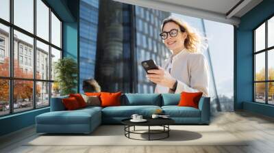 Uses a phone device in his hands, communicating with a colleague. A woman with glasses is a marketing expert working in an office. Wall mural