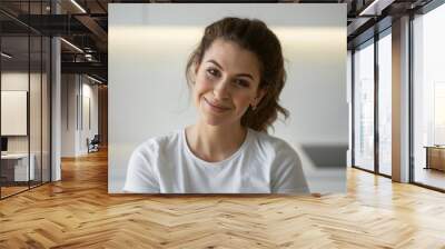 woman is sitting at home in the kitchen in front of a gadget, looking at the camera, a student Manager is typing a message and writing on a computer laptop work on distance learning. copy space Wall mural