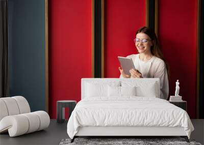 Writes a message in a chat a woman with glasses works uses a tablet in an office in a coworking space Wall mural