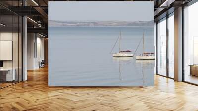 Two very similar sailing boats on calm water with reflection. Serene scene tranquil landscape. Wall mural