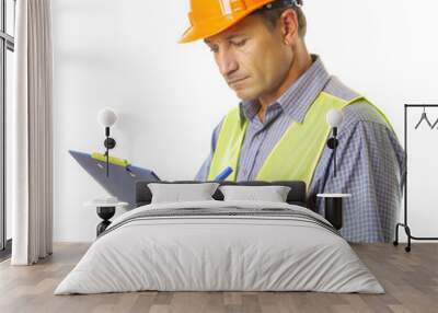 A man wearing a hard hat and safety vest is writing on a clipboard Wall mural