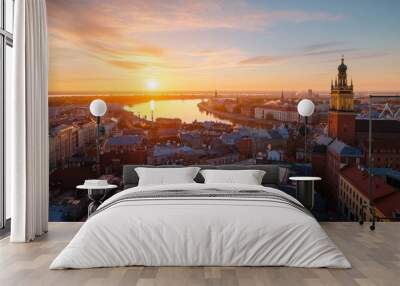 Panoramic view of Riga at sunset from a rooftop shows the city's buildings and the Daugava River. The old part of the city can also be seen in the view. Wall mural