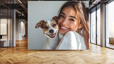 A young woman kisses her puppy Jack Russell terrier dog. Love between owner and pet. Studio portrait. Wall mural