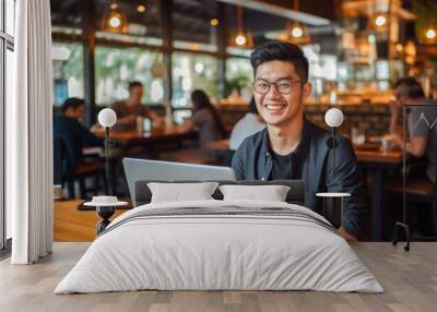 Asian man working on a laptop computer in a busy cafe in the city, a portrait of a successful man Wall mural