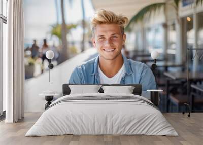 Beautiful attractive young man with blonde hair. Enjoying outdoors at a lively boardwalk lined with shops and restaurants, emphasizing a carefree spirit Wall mural