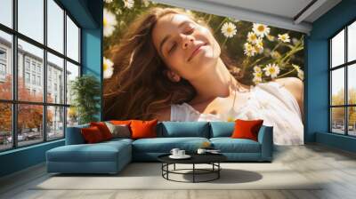 Beautiful young woman lying in a field of chamomile flowers. A serenity, peace, and bliss expression, connection with nature reflect gratitude and contentment and tranquility Wall mural