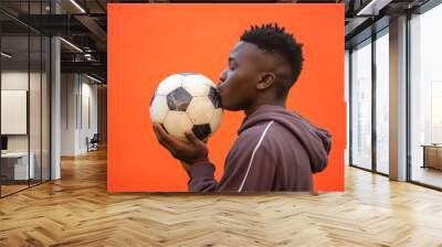 Black African young man in love with football sport kissing a soccer ball Wall mural