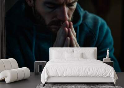 Close up of man praying with hands clasped together against dark background Wall mural