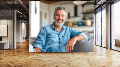 Happy middle aged man sitting on sofa at home, a single mature senior in living room Wall mural