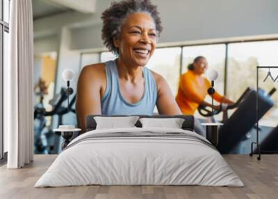 Middle aged African American woman on stationary exercise bike at gym, maintaining a healthy lifestyle, focused on exercises Wall mural