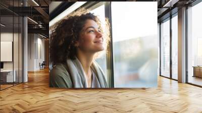 Pensive young woman, happily gazing out the window during her morning commute on an urban light rail train, expressing gratitude Wall mural