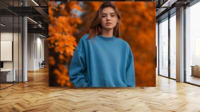 Portrait of a young woman wearing a crewneck blue mockup sweatshirt with fall colors and themed background for autumn season female fashion Wall mural