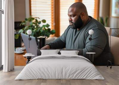 Portrait of an overweight African American man working from home on a laptop computer Wall mural