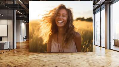 Young happy smiling woman standing in a field with sun shining through her hair Wall mural