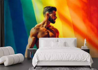 Young shirtless muscular man posing in front of rainbow background in gay concept shot Wall mural