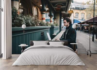 Younger man using a laptop in the middle of London. Student or freelancer lifestyle. High quality generative ai Wall mural