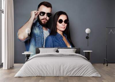 A young stylish fashion couple in casual clothes with black glasses look at the camera on a gray background. Wall mural