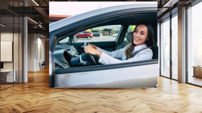 Beautiful happy successful businesswoman is driving a new modern car in good mood. Wall mural