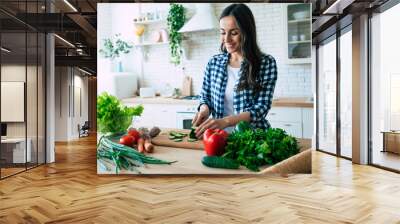 Beautiful young woman is preparing vegetable salad in the kitchen. Healthy Food. Vegan Salad. Diet. Dieting Concept. Healthy Lifestyle. Cooking At Home. Prepare Food. Cutting ingredients on table Wall mural