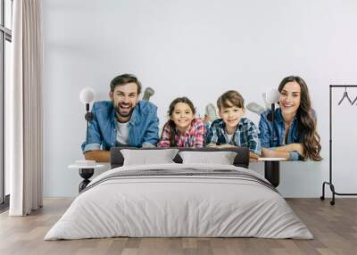 Close up photo of smiling beautiful modern family lying on the floor and looking on camera Wall mural