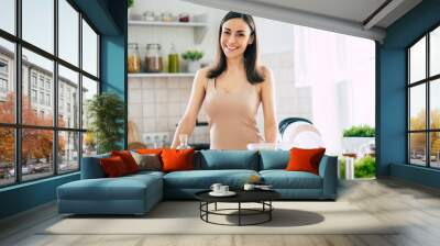 Cute happy young brunette woman in good mood preparing a fresh vegan salad for a healthy life in the kitchen of her home Wall mural