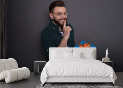 Excited handsome bearded man in casual wear in good mood with big gift box in his hands shows surprise gesture over gray background Wall mural