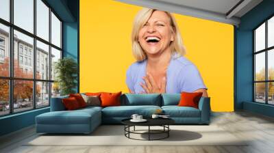 Happy smiling beautiful cute lovely blonde senior woman with beauty clean skin in casual wear isolated on yellow background. Healthcare and cosmetology concepts. Pensioner and mature people Wall mural