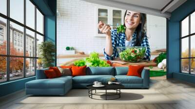 Healthy lifestyle. Good life. Organic food. Vegetables. Close up portrait of happy cute beautiful young woman while she try tasty vegan salad in the kitchen at home. Wall mural