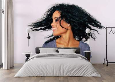 I whip my hair back and forth. Charming Afro-American lady with frizzy dark hair is whipping her hair with her eyes closed while laughing with joy. Wall mural