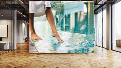 Photo of female legs while she trying the water in hotel pool. Vacation and recreation in the spa Wall mural