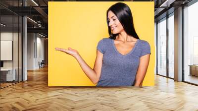 Photo of young excited beautiful happy brunette woman, girl pointing away and smile isolated on yellow background banner Wall mural